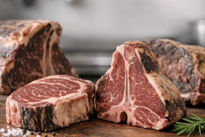 Raw dry-aged steaks on a wooden board with coarse salt and rosemary, ideal for dry aged etler.
