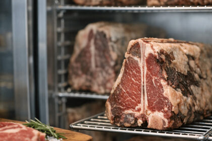 Dry-aged beef steaks on metal racks inside a refrigerated dry aged dolabı meat aging cabinet.