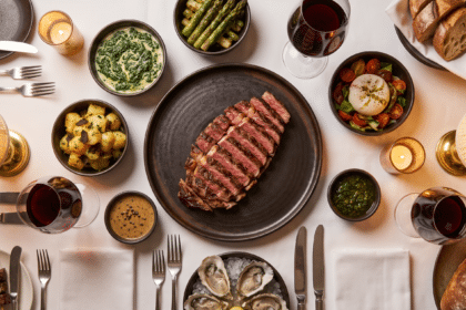 Steakhouse masasında dilimlenmiş biftek tabağı ve çevresinde küçük kaselerde mezeler, garnitürler ve soslar
