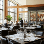 Gün ışığı alan modern steakhouse salonunda öğle servisi ve arka planda dry aged vitrini