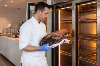 Kasap, dry aged dolabından dinlenmesi tamamlanmış koyu kabuklu bir dana kütüğünü çıkarıyor