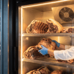 Kasap, dry aged dolabında bir et parçasını alt raftan üst rafa alarak konum rotasyonu yapıyor